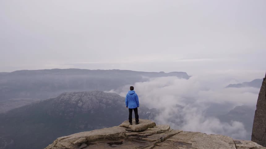 A man is perched on the edge of a mountain top