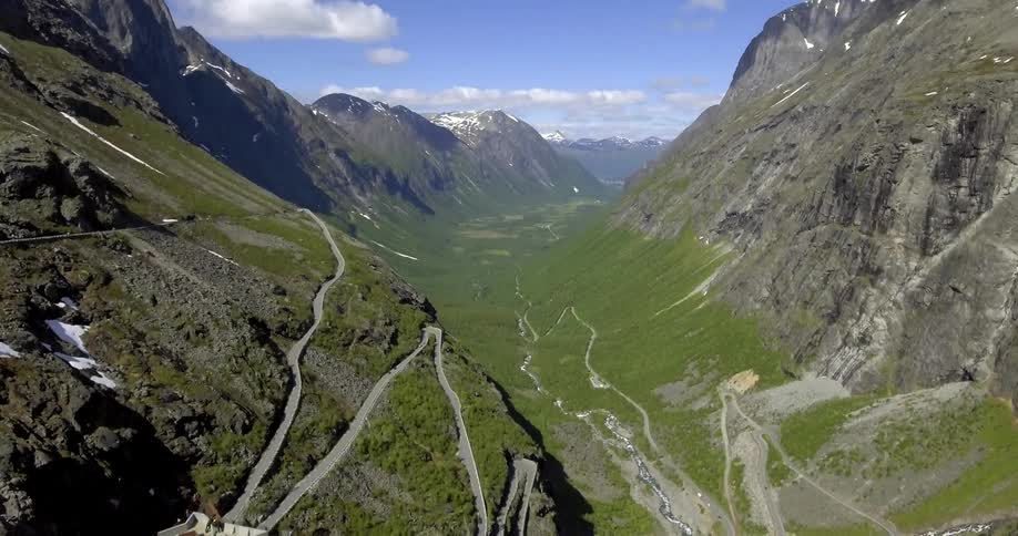 Two people sit on the edge of a mountain and look over the ravine below