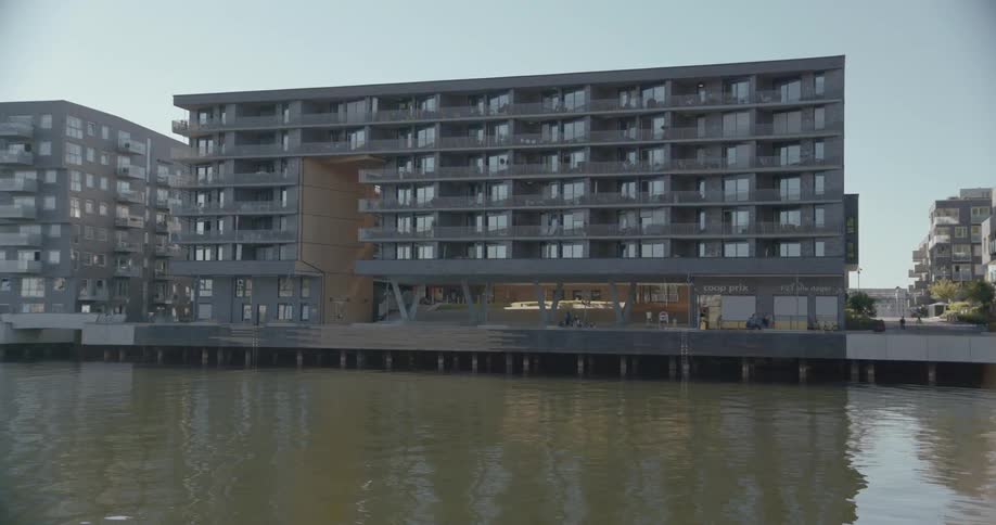 A body of water leads to a row of buildings with people walking nearby