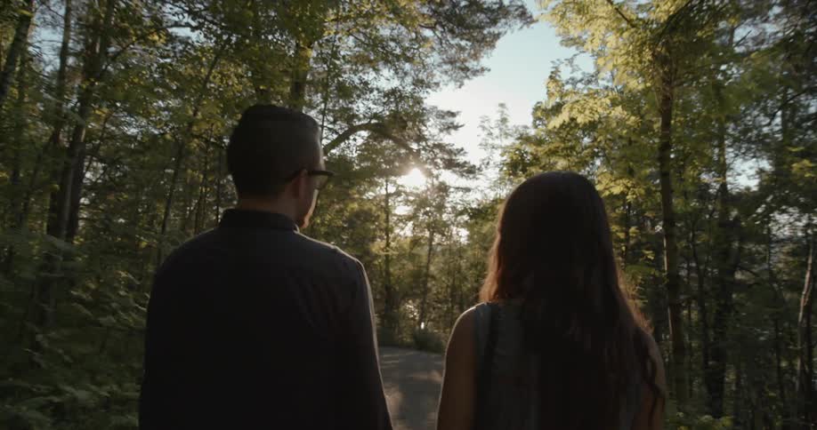 A man and women are walking along a trail in the woods
