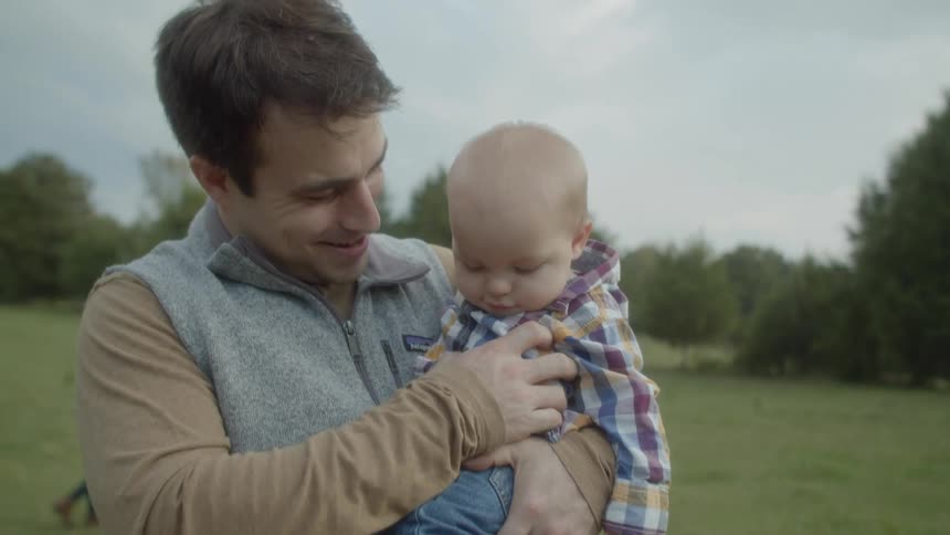 A father is outdoors with his two songs