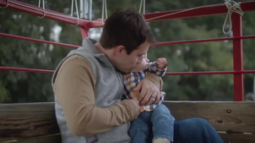 A man holds a baby sitting on a large moving wagon outside