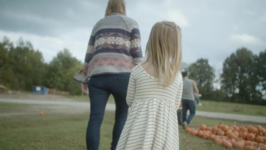 A mother and father walk with their three children at a pumpkin patch