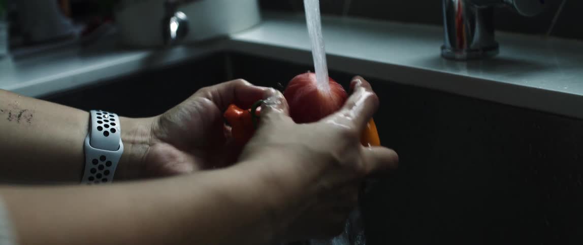 A person washing vegetables on the kitchen sink