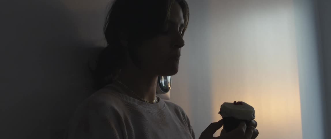 A woman at home eats a cupcake