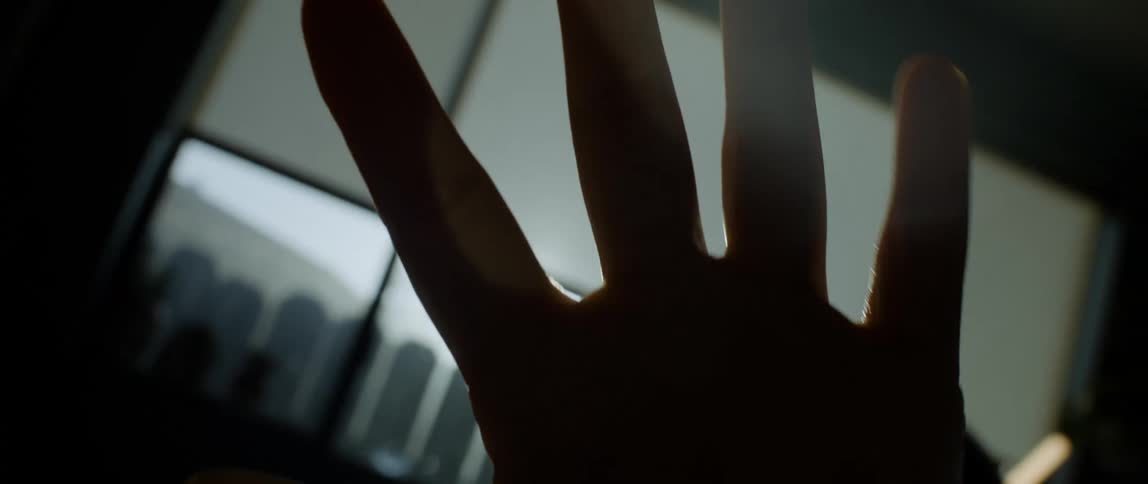 Sunlight filtering throught the silhouette of the hand of a person inside a dark room