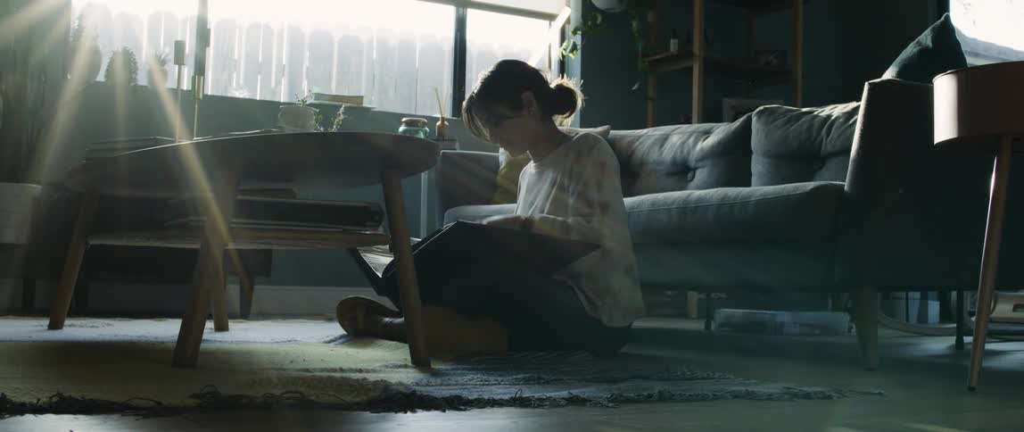 Young woman sitting on the floor of the livingroom reading a book
