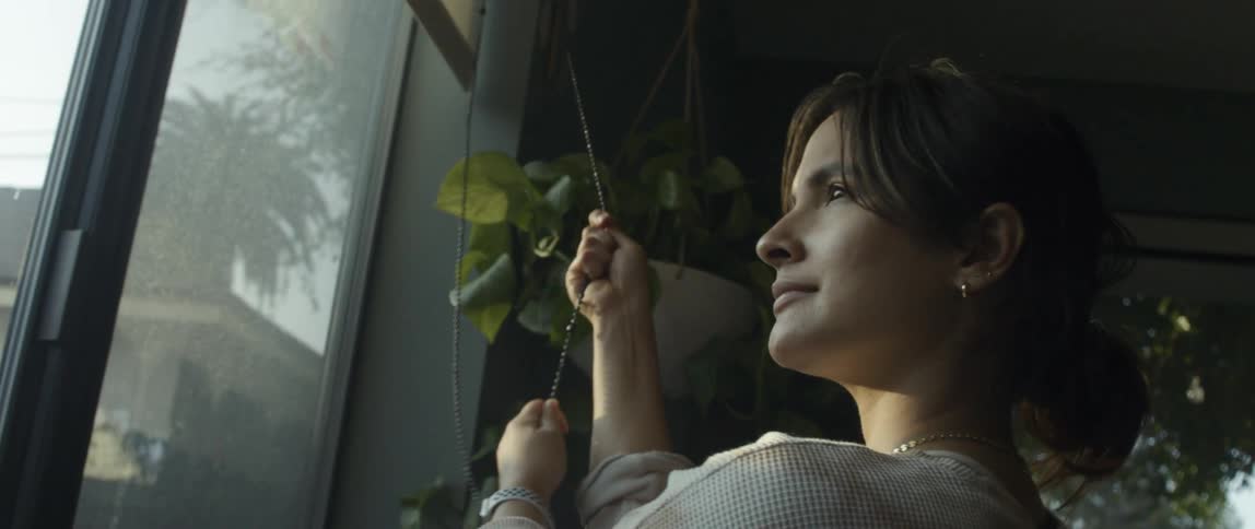Woman lifting the curtain inside a room at morning