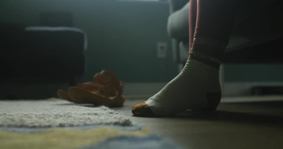 A person stands on the floor of the living room only wearing socks at morning
