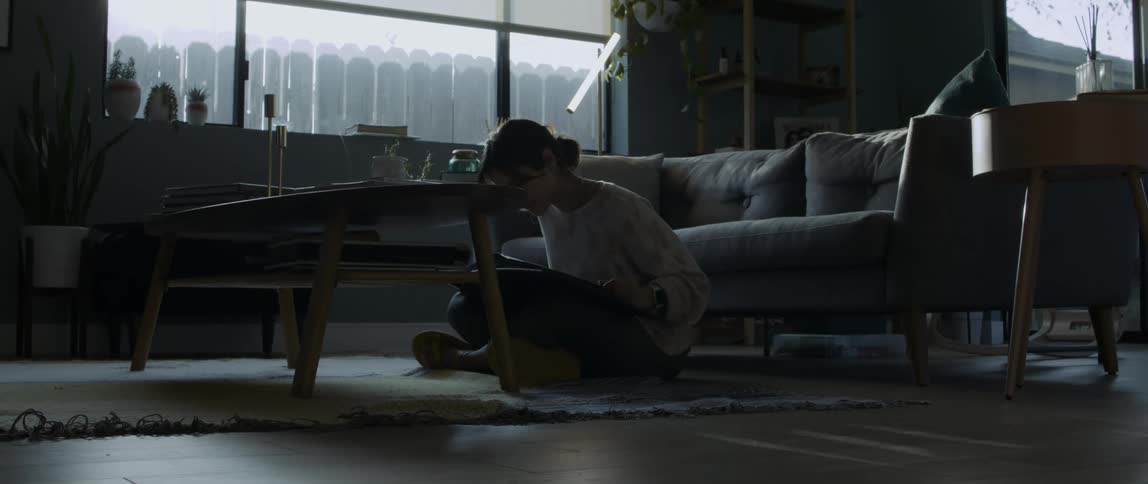 Woman reading a book sitting over the rug in the floor of the living room at sunset