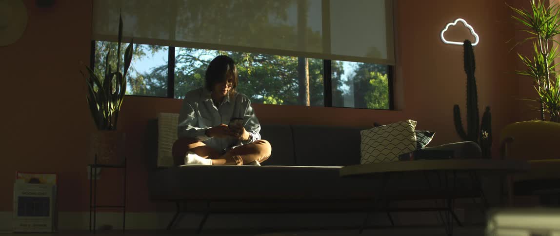 A person in a room sitting on a couch holding a smart phone