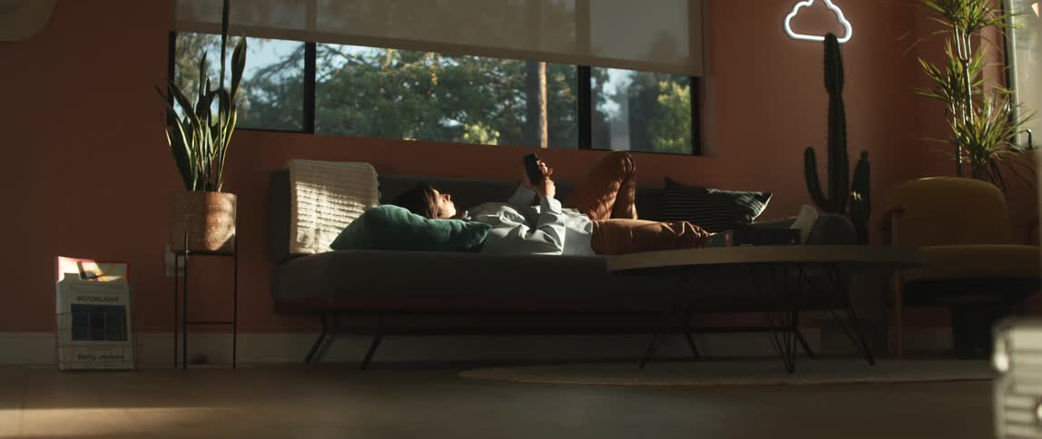 Woman realxing in the couch on the living room using a smartphone in the morning