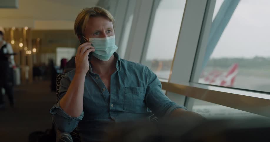 A man sits in a restaurant by a large window talking on his cell phone