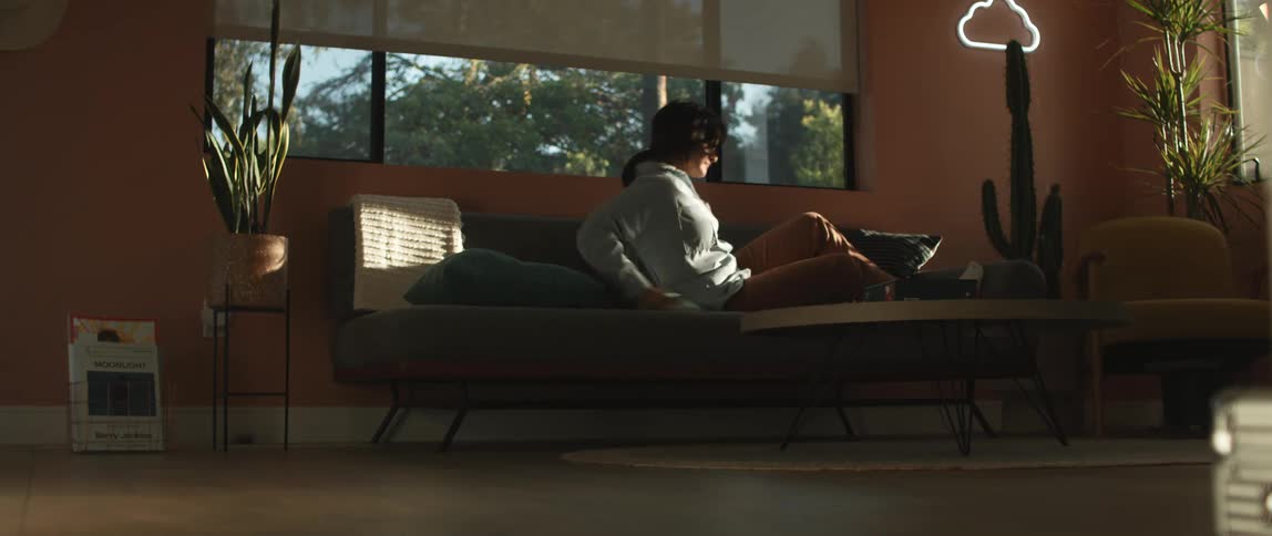 Young woman laying on the couch stops reading and sits up