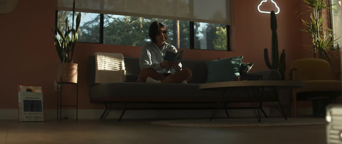 Young woman trying to read a book while sitting on a couch at home in the morning