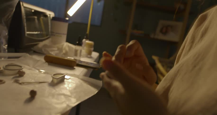 Woman sculpts clay with her hands and forms a design then sets her creation on a table with other clay designs