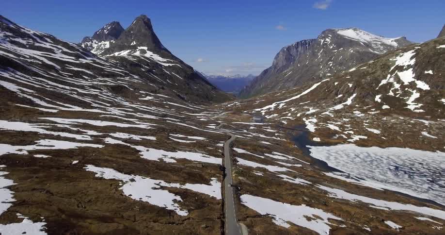 Aerial view of a car driving down a row near a mountain range