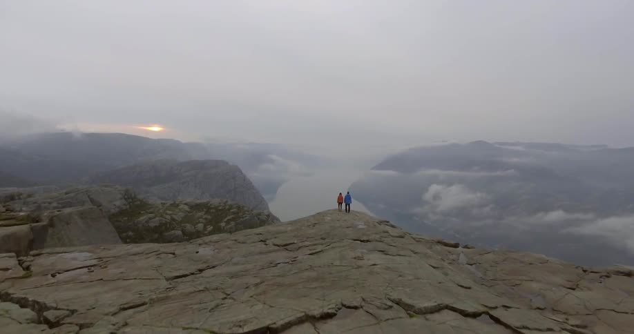 Two people are standing together on the edge of a cliff