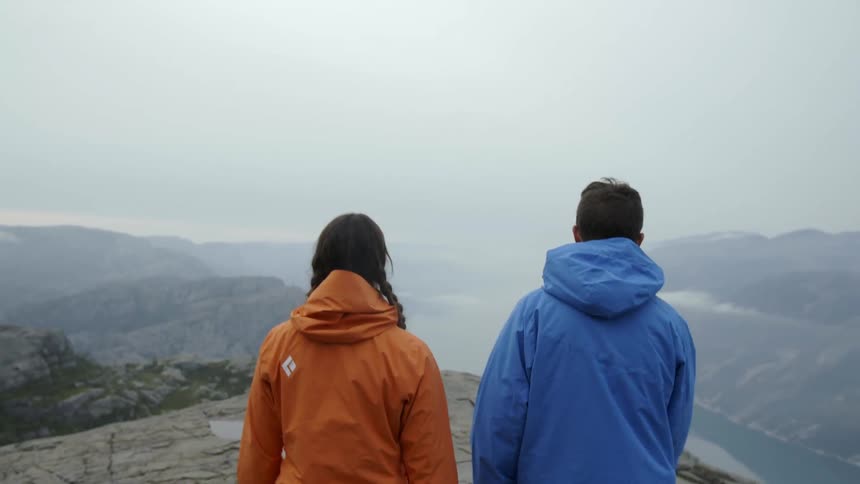 Two people are walking to the edge of a cliff