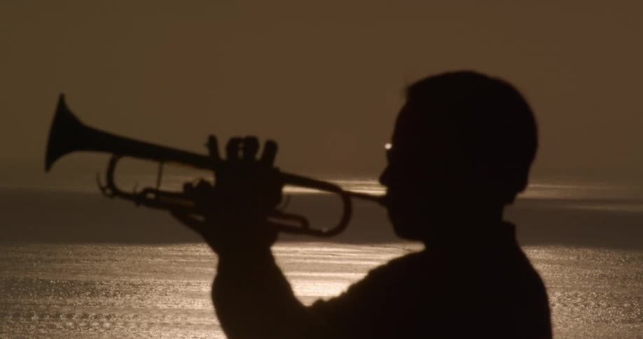 A man on the shore playing a trumpet