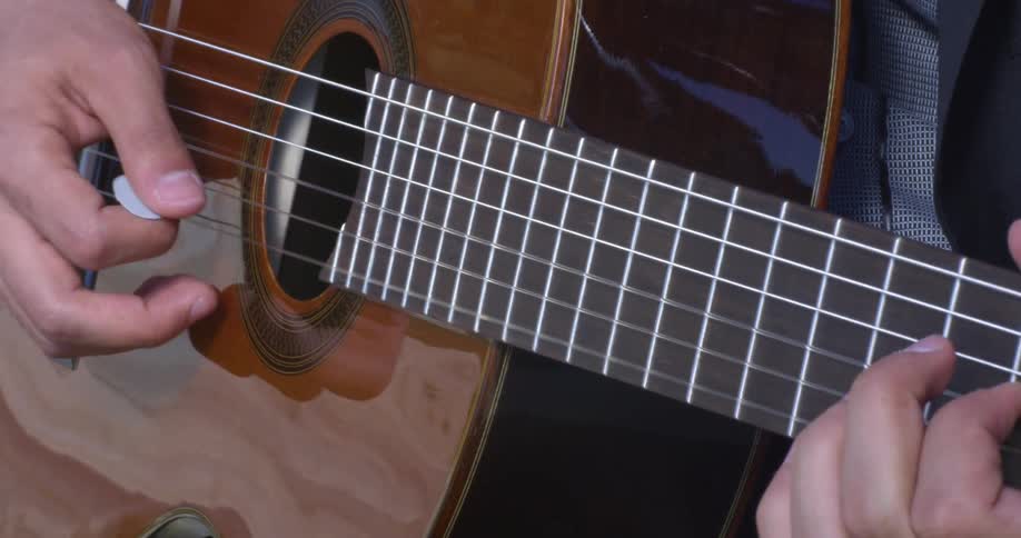 A man plays a guitar with his fingers and a pic