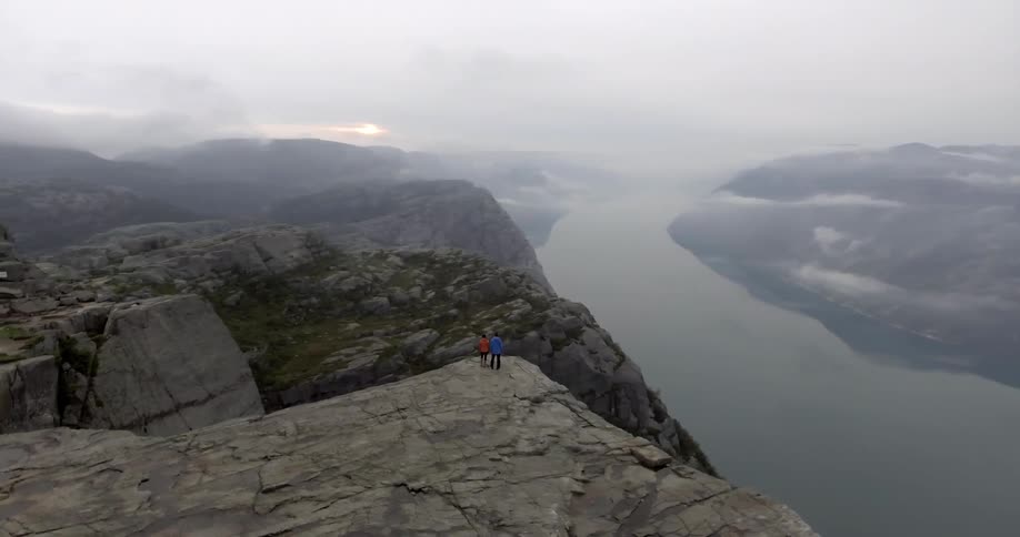 Two people stand on the edge of a mountain