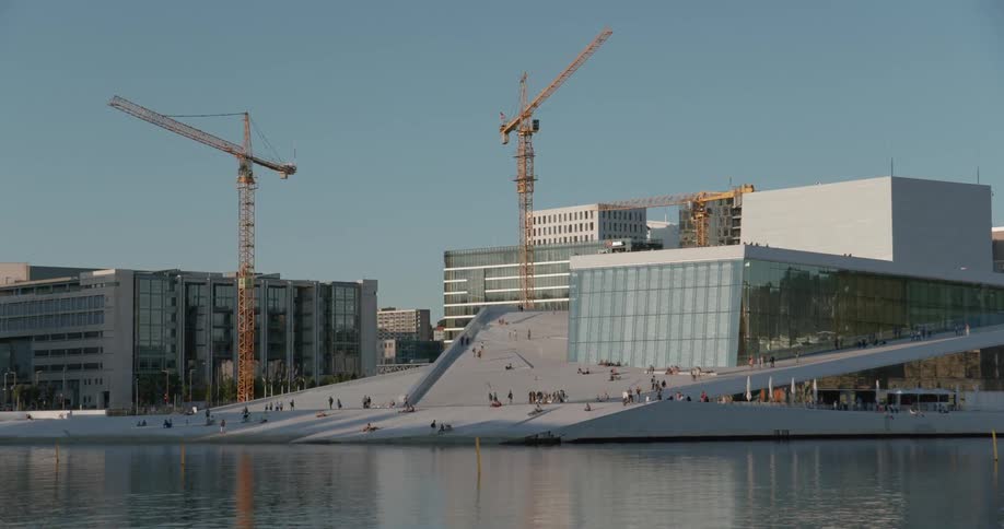 Buildings line the water as people walk near the shore