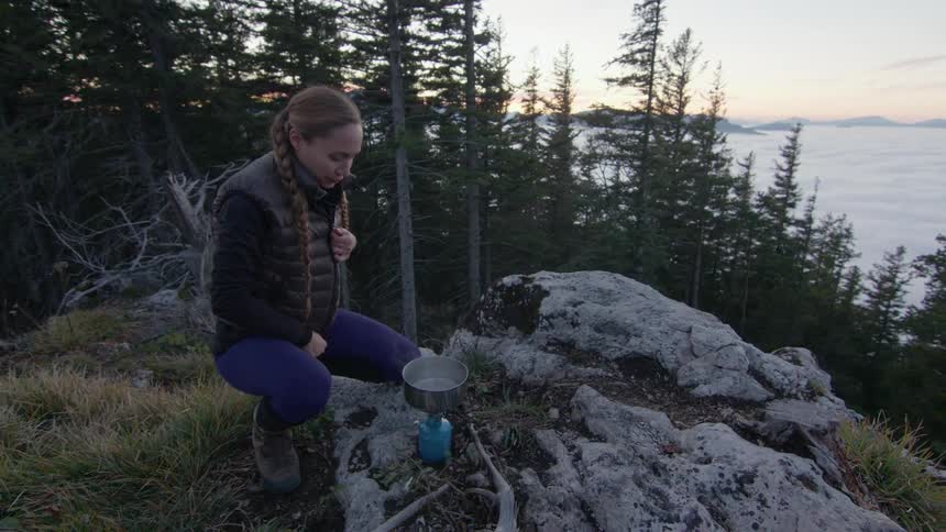A woman is boiling water on a mountain