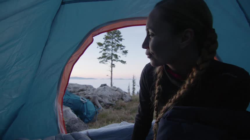 A woman resting in a tent sits upright and looks refreshed