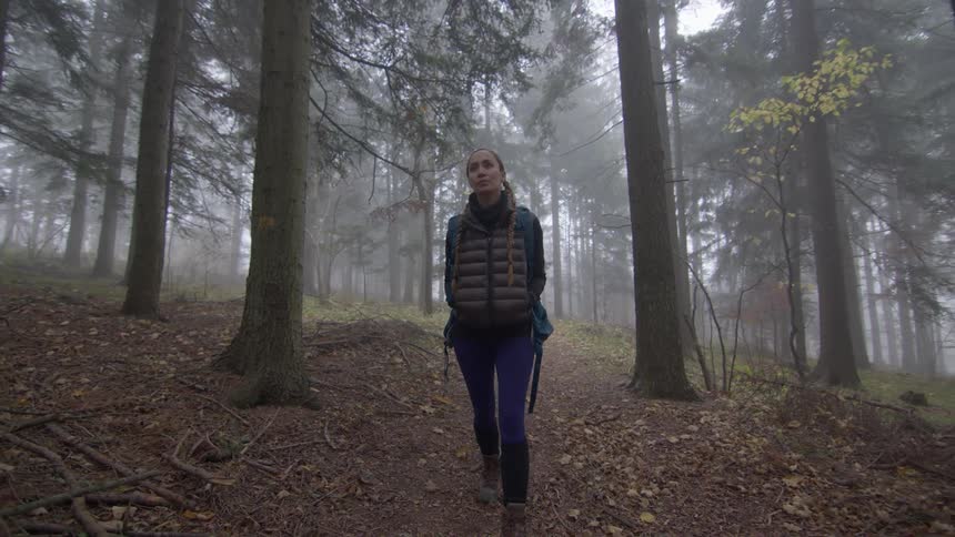 Girl is walking through the forest on a foggy day
