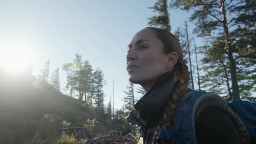 A woman is hiking outdoors through the forest