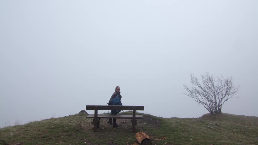 A woman walking to a bench and sitting down