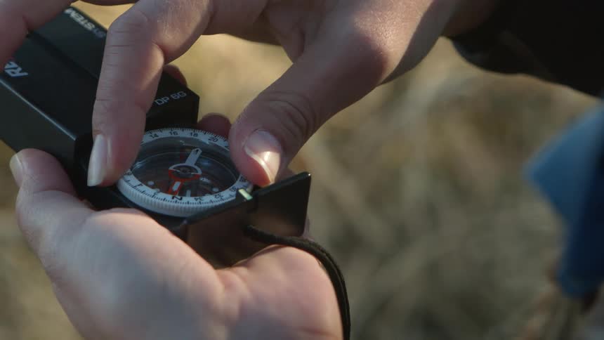 A woman outside adjusts a compass