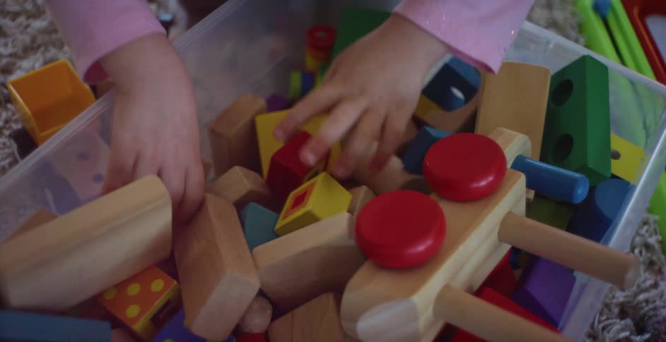 A young girl searches through a plastic tube full of toys