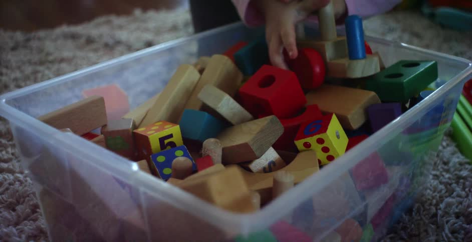 Small girl digs though toy bin filled with blocks