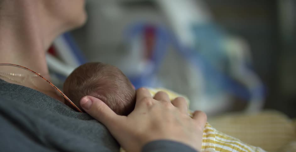 A mother holds her newborn baby in the hospital