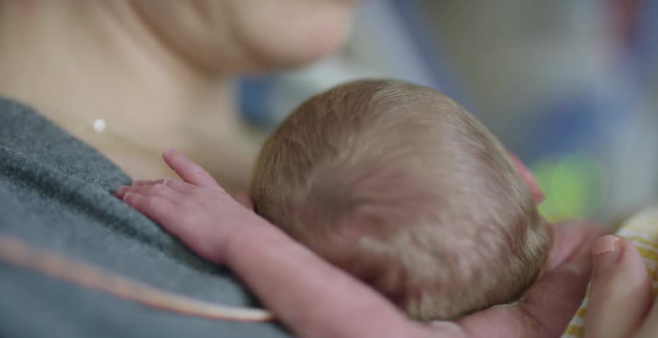 A mother is holding a sleeping newborn in her arms