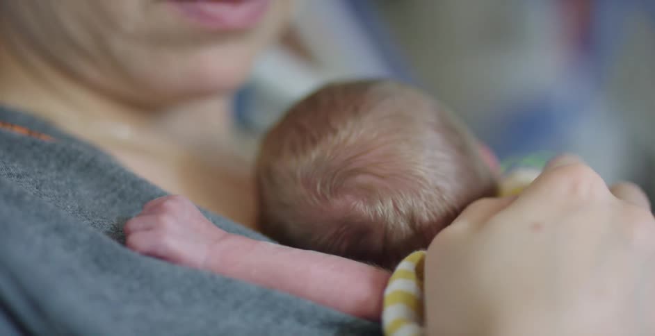 Mother holding newborn baby on her chest in the hospital