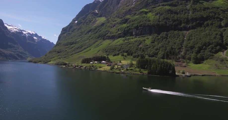 A speedboat moves down a body of water in a mountainous landscape
