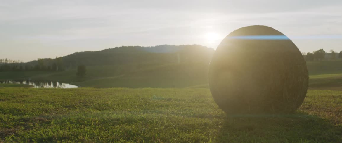 A hay bale on a farm field with sun glint