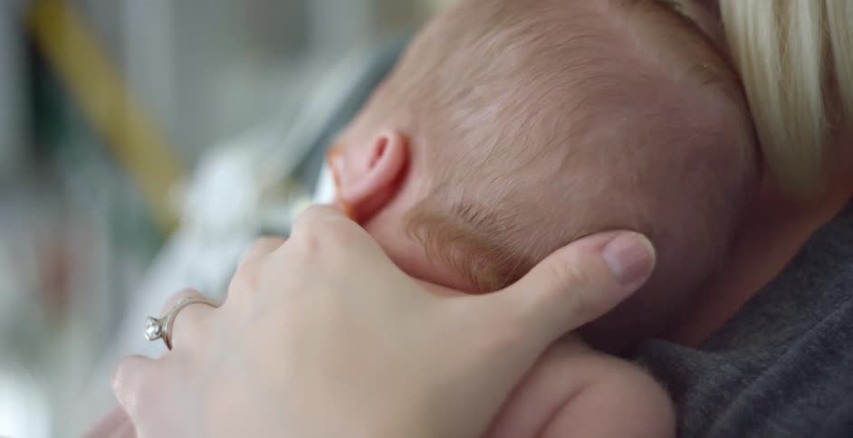 Mother holding newborn baby on her chest in a hospital room