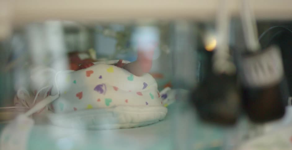 Baby laying on his back inside an incubator in a hospital