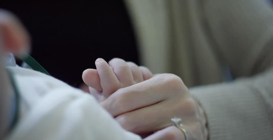 A close up of a parent holding a babys hand