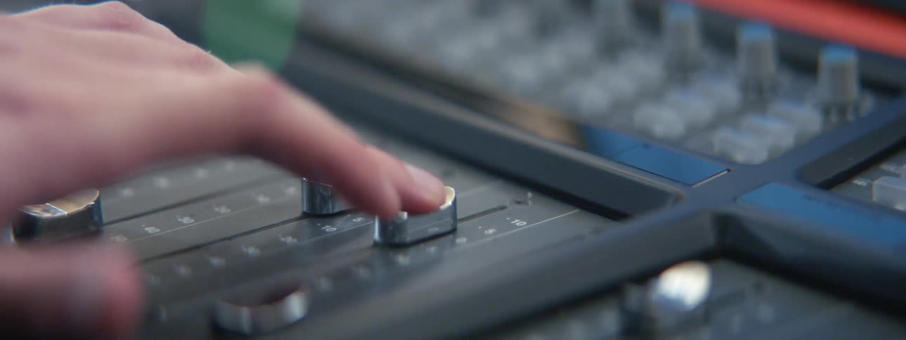 A close up of someone using an audio mixer