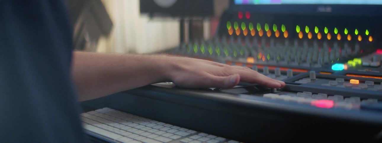 A person adjusts a board with their hand behind a keyboard while sitting at a table
