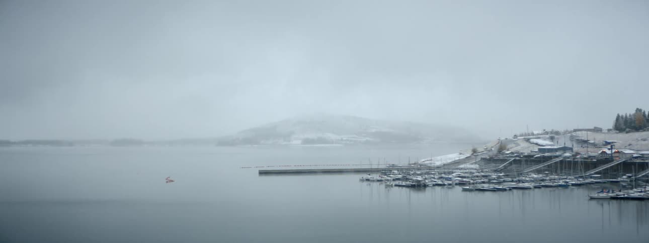 Boats on a harbor in the calm waters of a lake near the mountains at winter