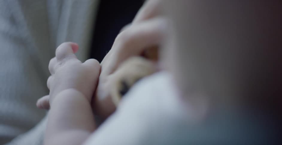 A baby sitting with the bare arm and hand with fingers moving