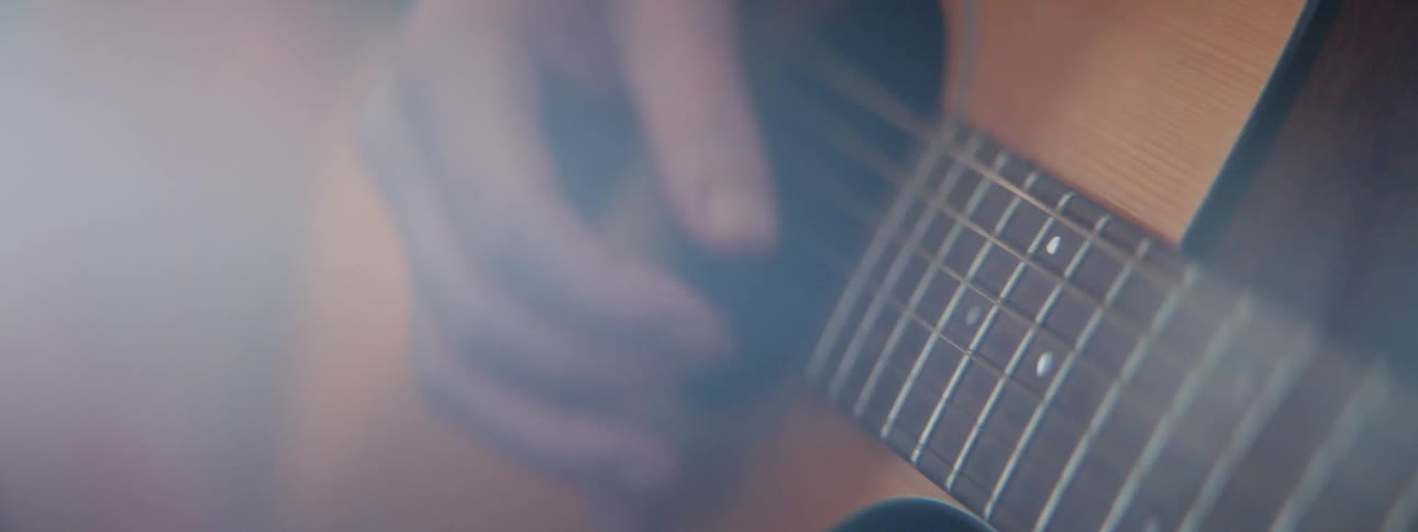 A person is strumming on the strings of an acoustic guitar