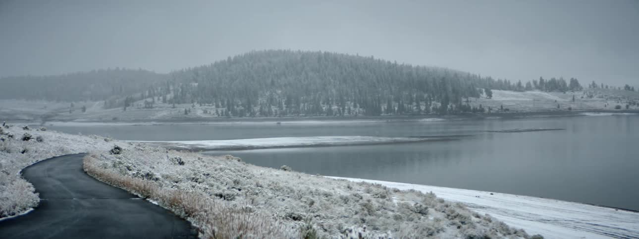 Snow covers the ground and hills that surround a lake