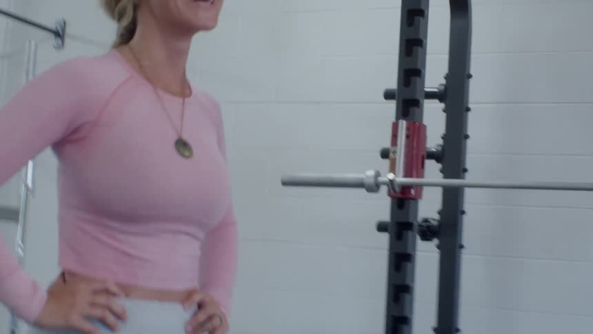 A woman laughs while catching her breath in a fitness gym